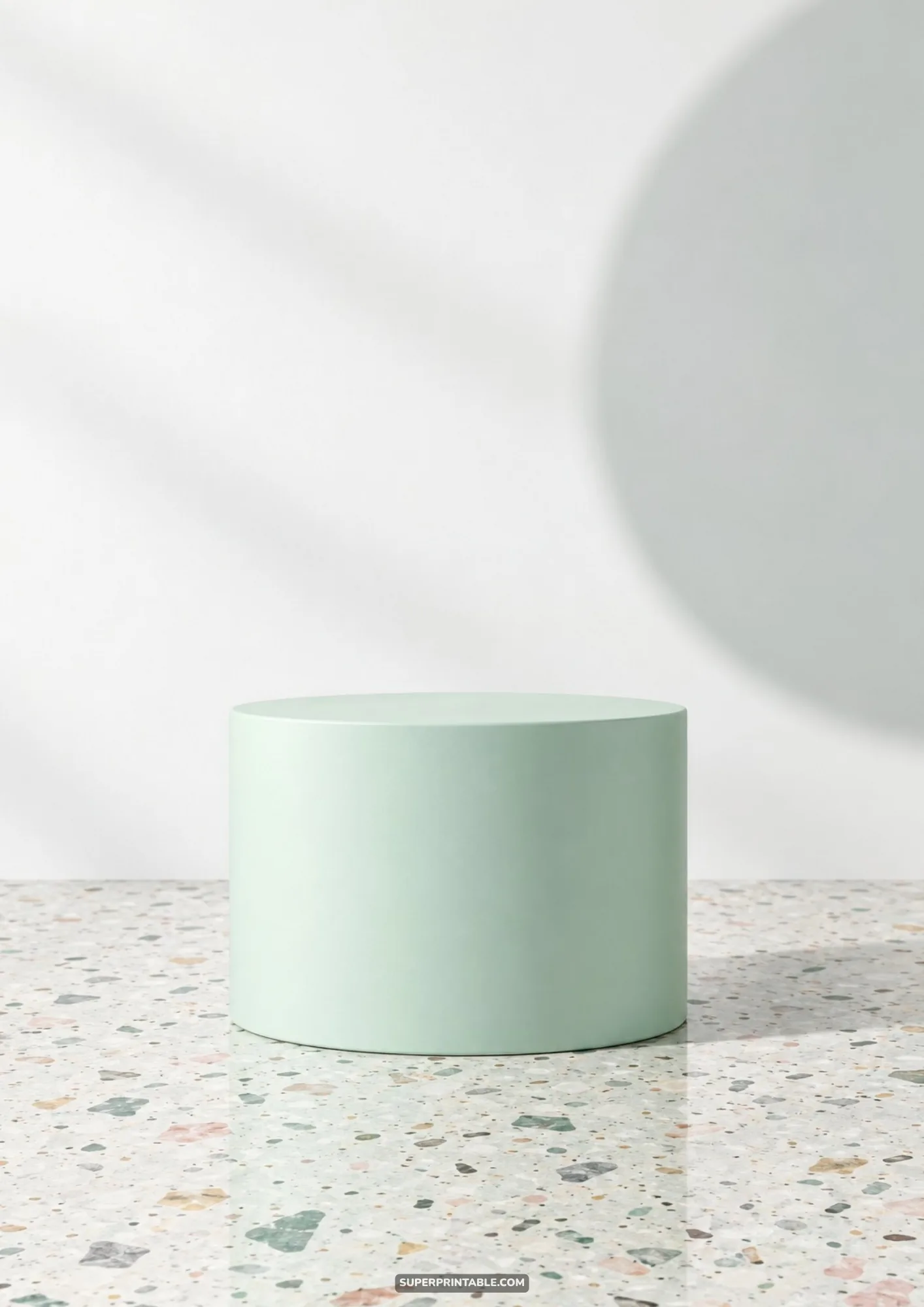 Pastel mint green cylindrical podium resting on an elegant speckled terrazzo surface against a white wall