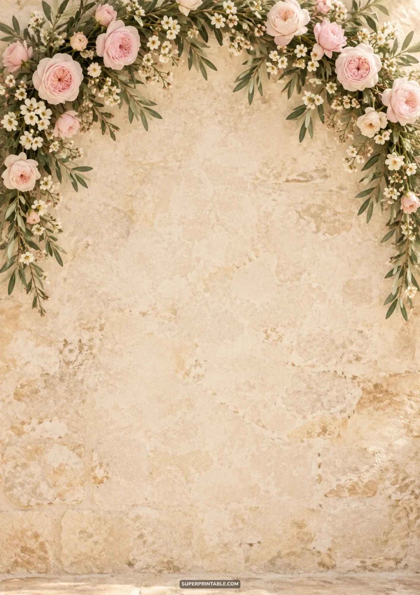 Lush blush rose and olive leaf garland hanging along the top of an antique stone wall backdrop
